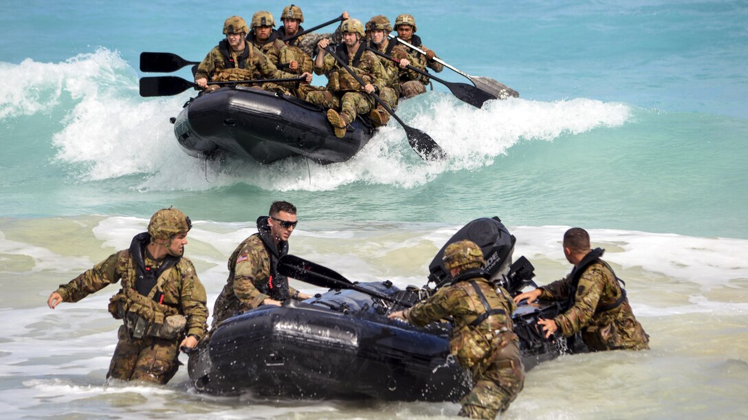 Soldiers make a beach landing with combat rubber raiding craft.