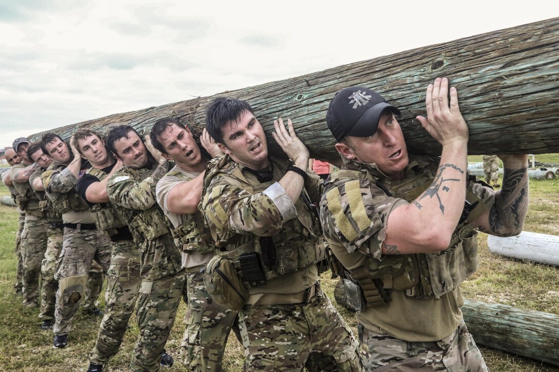 Soldiers lift and carry a log during an endurance event.