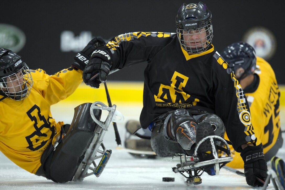 Two wounded warriors play hockey on an ice rink.