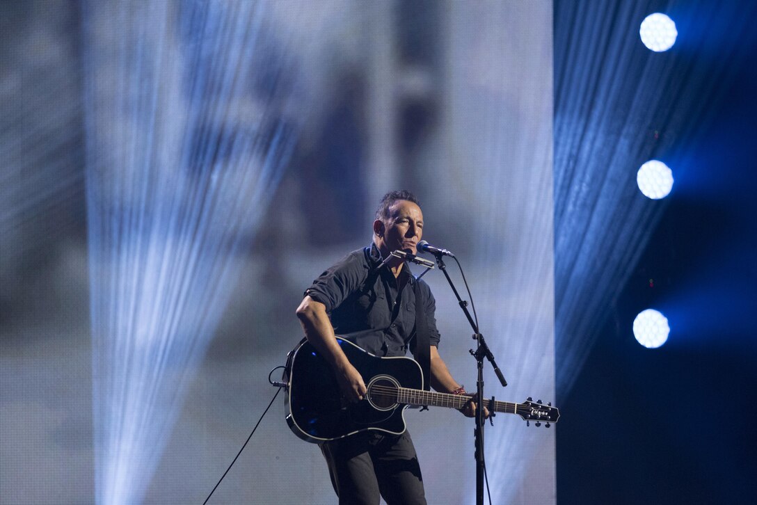 Bruce Springsteen plays guitar during a performance on stage.