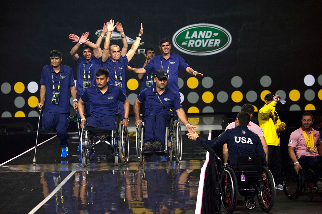 A group of people on stage is high-fived by a person in a wheelchair off stage.