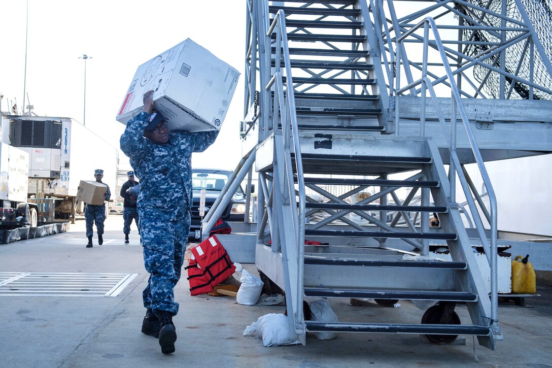 A sailor loads supplies onto a military hospital ship.