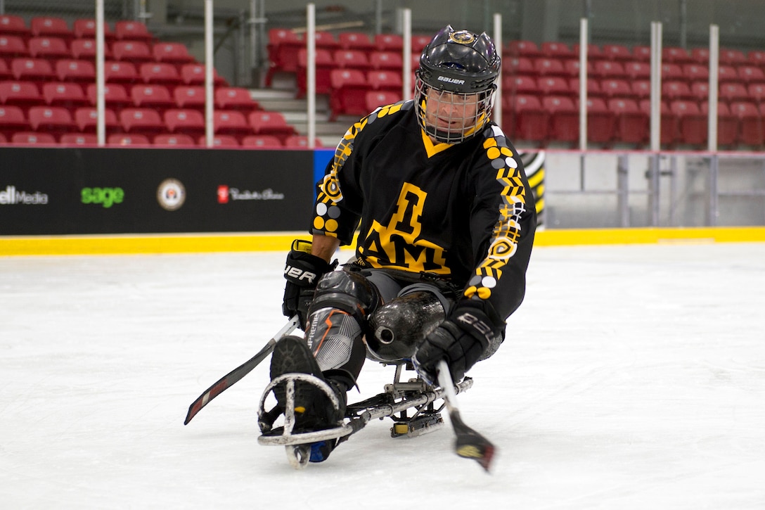 A sled hockey player hits a puck.