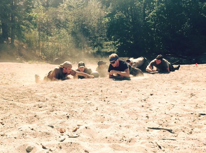 Service members crawl on desert terrain.