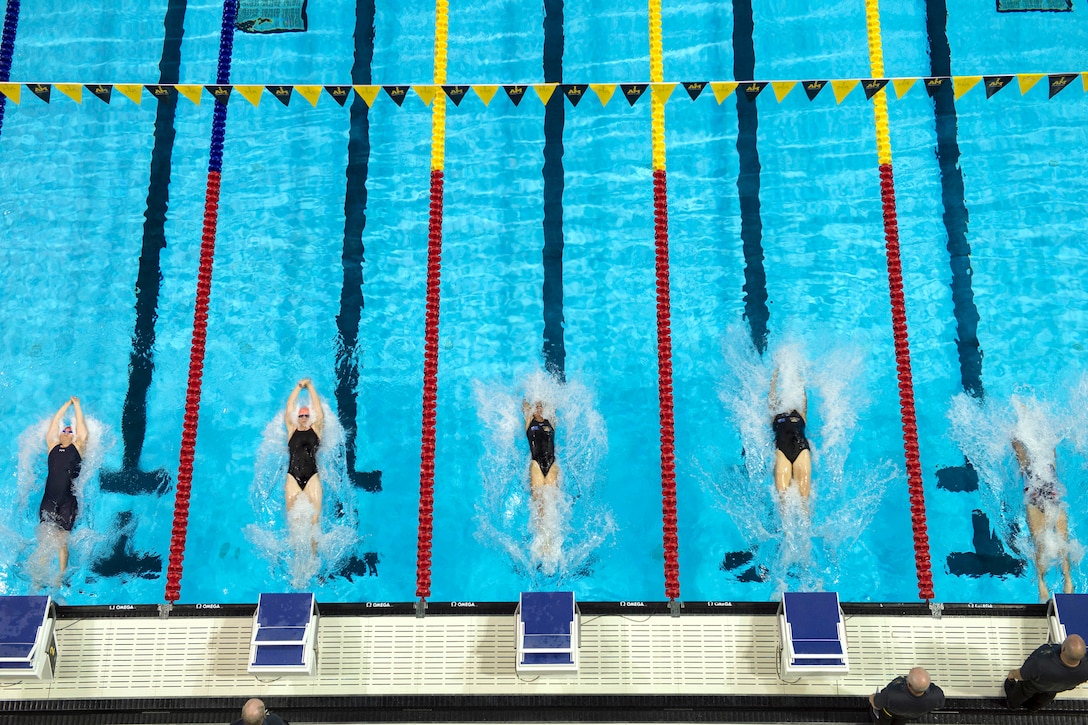 Swimmers push off at the start of a backstroke event.