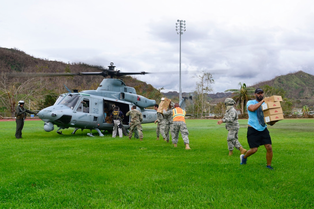Service members unload supplies from a military helicopter.