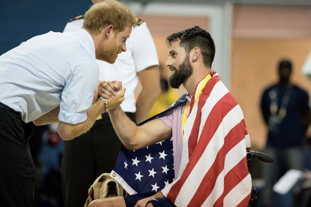 Britain's Prince Harry shakes hands with an Army veteran who won a medal.