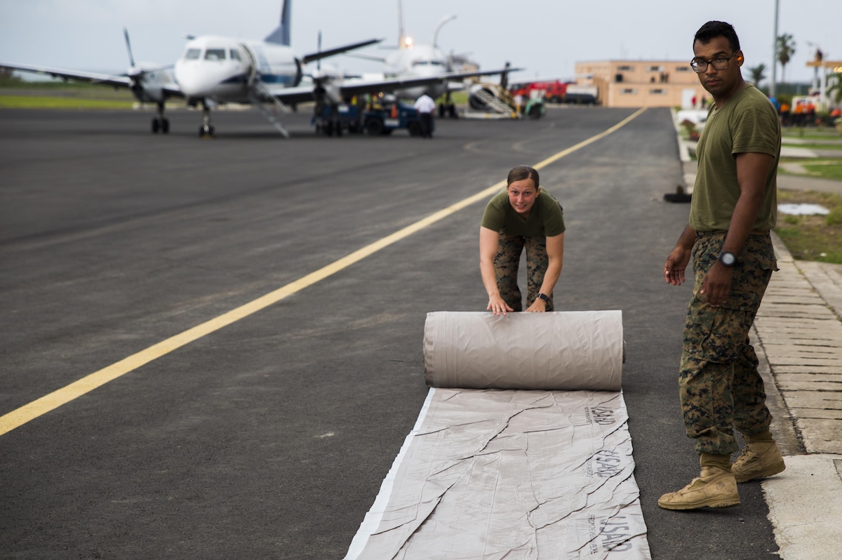 U.S. Marines with Joint Task Force - Leeward Islands unroll a tarp as they prepare supplies for distribution in Dominica