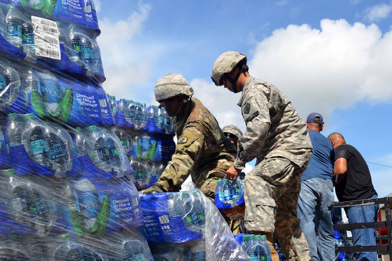 Soldiers load cases of bottled water onto a truck.