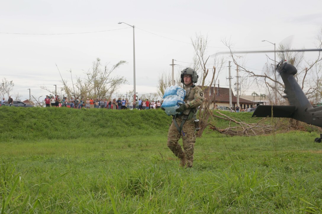 A soldier carries water he offloaded from a helicopter.