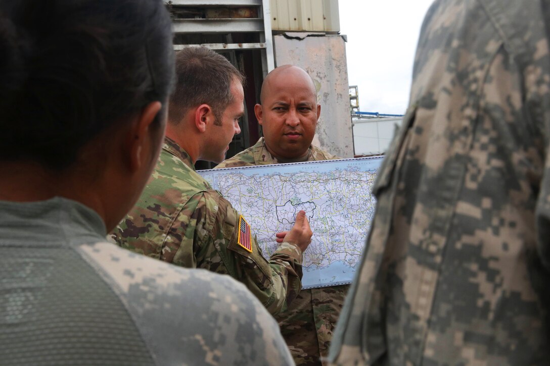 Army Cpt. Dustin Yates, center left, briefs and shows helicopter crews the towns they will be delivering supplies to in San Juan.