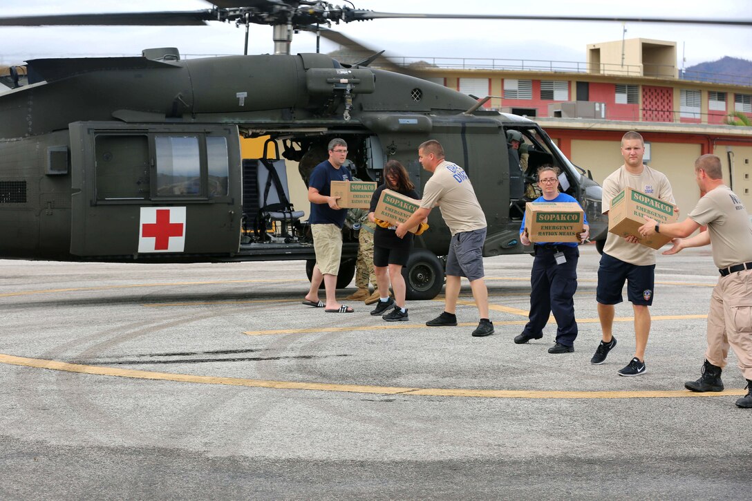 Soldiers offload supplies from a helicopter to a hospital.