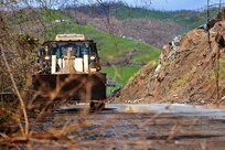 A Guardsman operates a bulldozer to remove debris and trees.