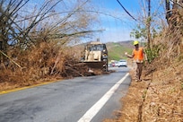 A Guardsman guides a bulldozer to clear debris and trees from roads.