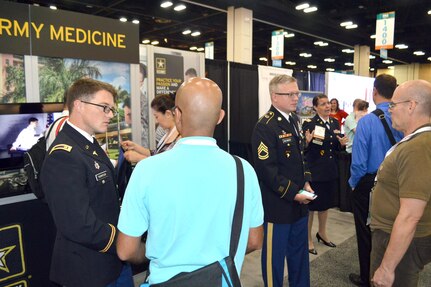 Army Maj. Timothy Thompson (far left), an active duty family medicine physician and teaching faculty member at the Martin Army Community Hospital Family Medicine Residency Program in Fort Benning, Ga., Army Sgt. 1st Class Chad McLaughlin (middle), lead recruiter for the San Antonio Medical Recruiting Center, and Army Lt. Col. Julie Hundertmark, Army Medical Corps recruiting integration officer with the Medical Recruiting Brigade at Fort Knox, Ky., speak with people at the American Academy of Family Physicians Family Medicine Experience 2017 or FMX 2017, Sept. 14 at the Henry B. Gonzales Convention Center in downtown San Antonio.