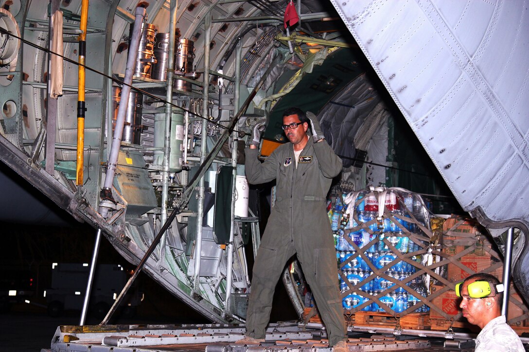 Service member waves in forklift with supplies.