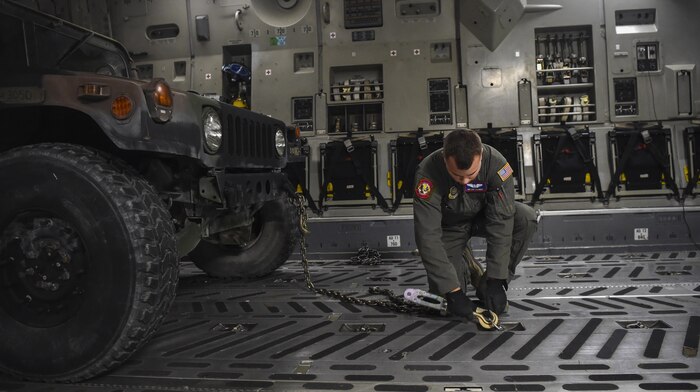 Airman 1st Class Patrick Schmidt, 15th Airlift Squadron loadmaster, secures a Humvee in the cargo bay of C-17 Globemaster III at Fort Drum, N.Y., Sept. 28th, 2017.
