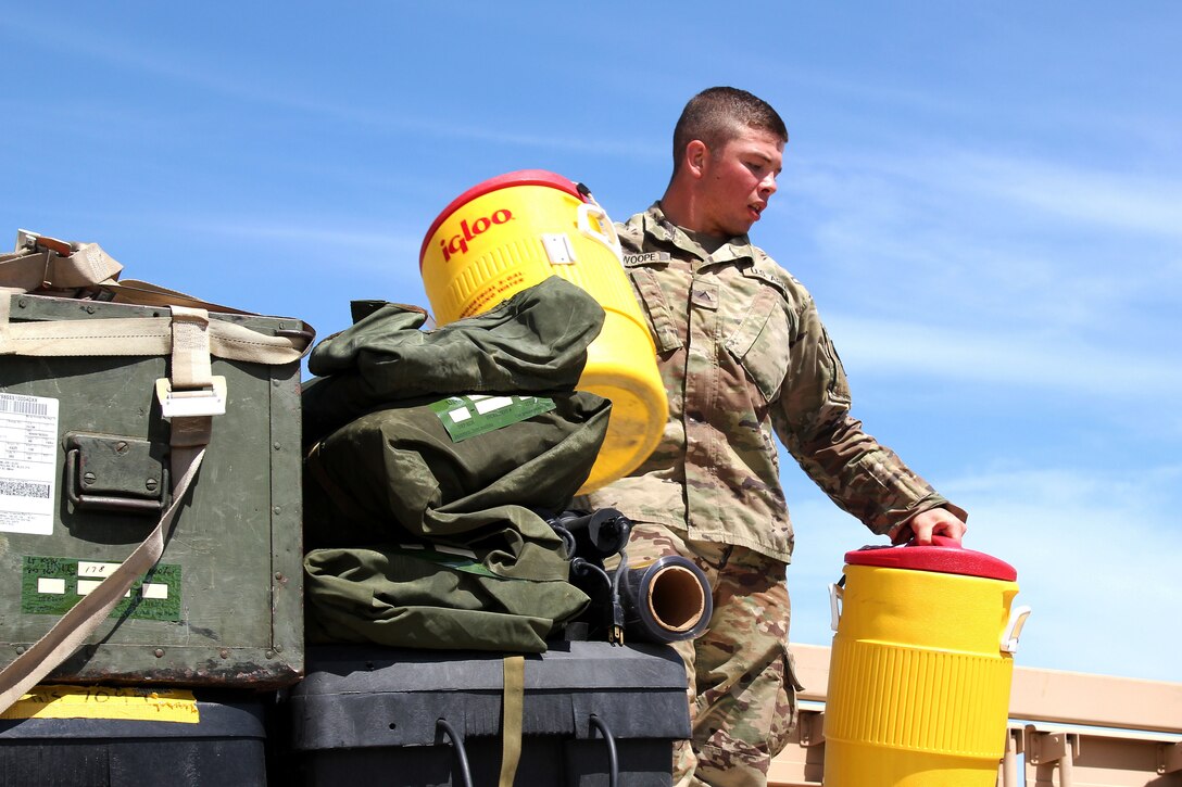 An airman hands coolers to an unseen person.