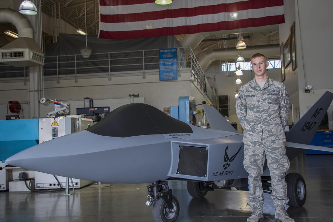 Airman 1st Class Brendan Picklesimer, 60th Maintenance Squadron aircraft structural journeyman, poses for a photo next to a model F-22 Raptor Sept. 21, in building 803. The model F-22 project was a large accomplishment for Picklesimer and his team.