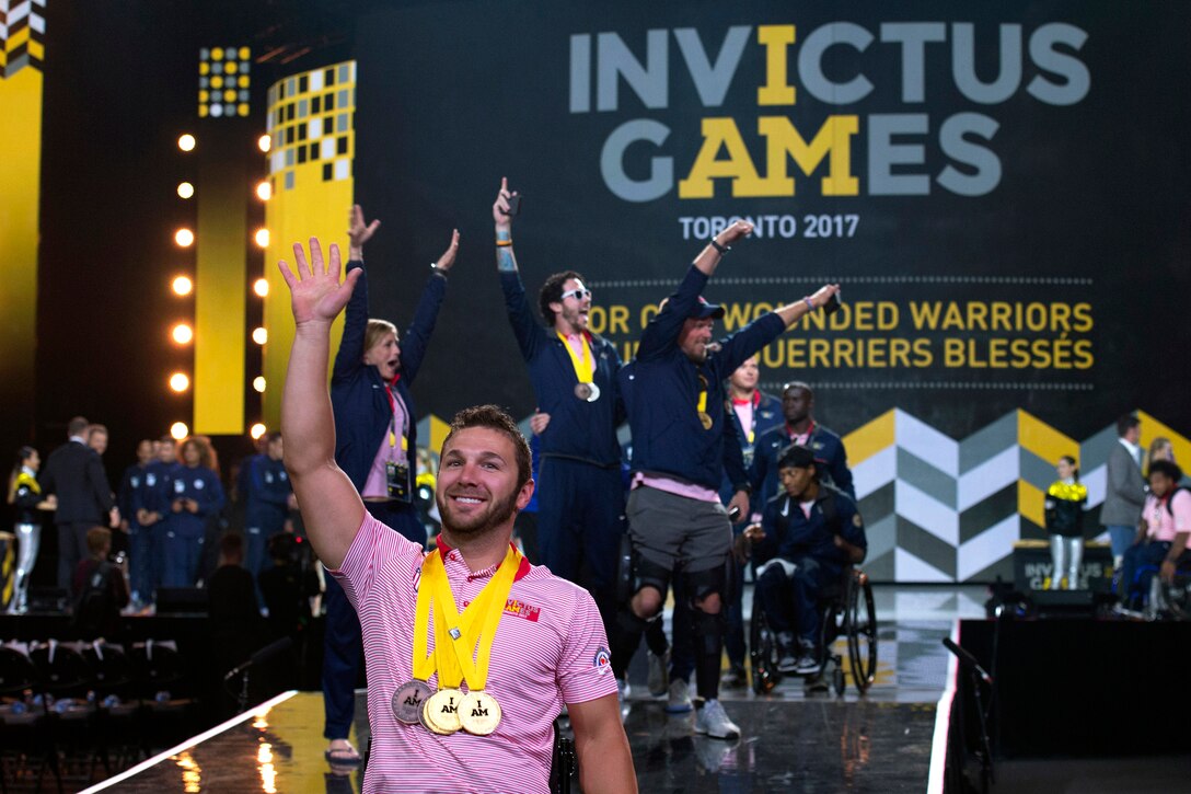 Navy Petty Officer 3rd Class Nathan Dewalt waves as Team U.S. enters the 2017 Invictus Games closing ceremony.
