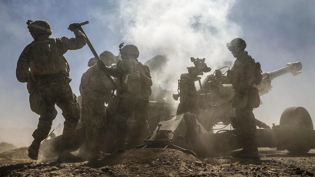 Marines create a cloud of smoke as they fire a howitzer.