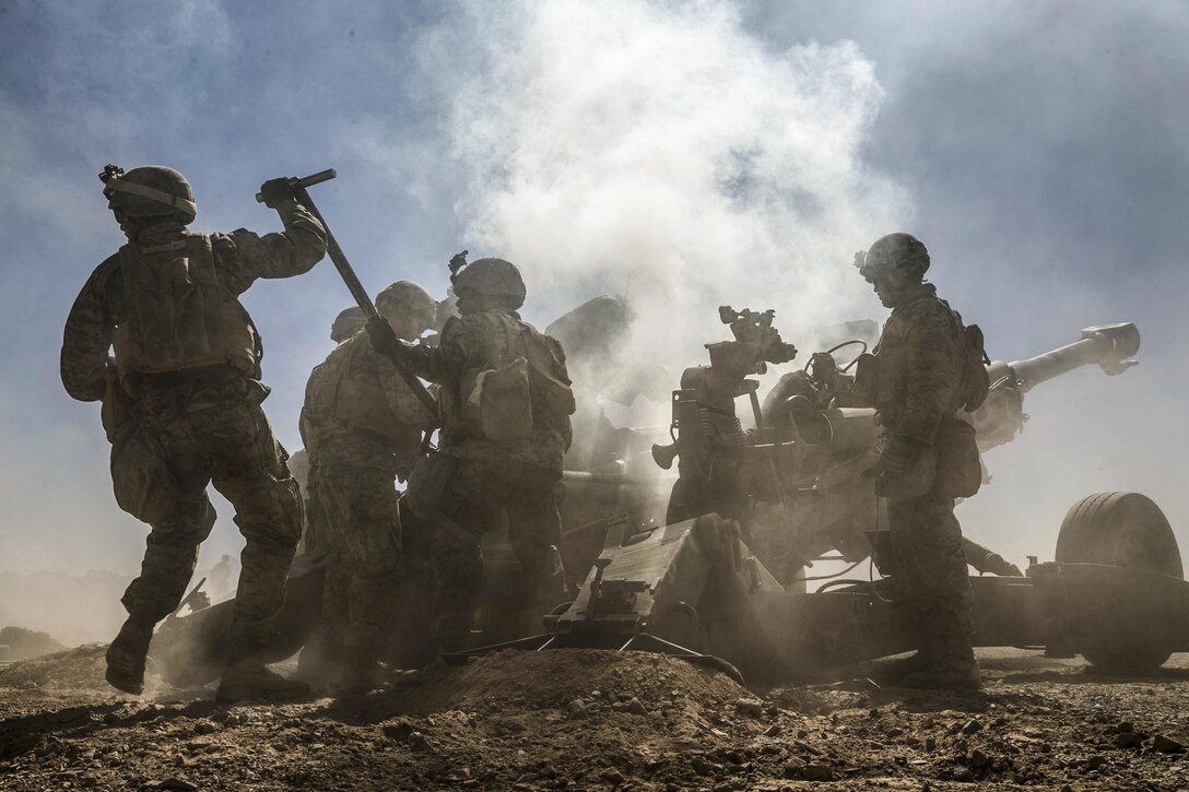 Marines create a cloud of smoke as they fire a howitzer.