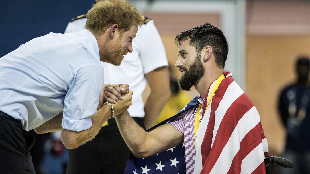 Prince Harry shakes hands with an Army veteran who won a swimming medal.