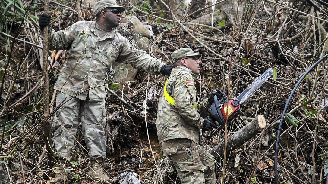 Soldiers help clear debris from roads after a hurricane.