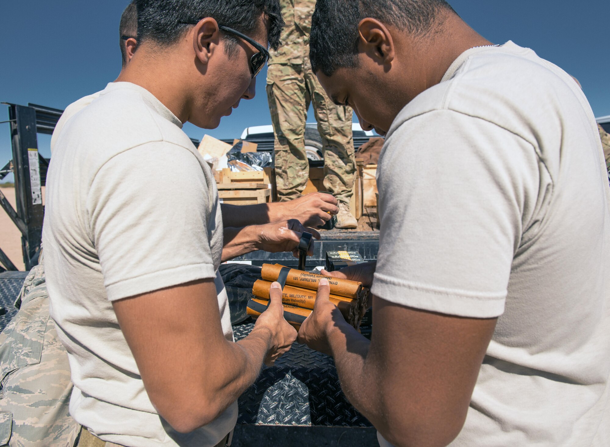 Senior Airman Tahir Finley, 56th Civil Engineer Squadron explosive ordinance disposal team member (left) and Airman 1st Class Christian Bish, 56th Equipment Maintenance Squadron munitions management apprentice, prepare sticks of dynamite for detonation at the Gila Bend Air Force Auxiliary Field in Gila Bend, Ariz., Sept. 21, 2017. Throughout the demolition day, EOD Airmen worked together to ensure safety when handling explosives. (U.S. Air Force photo/Airman 1st Class Alexander Cook)
