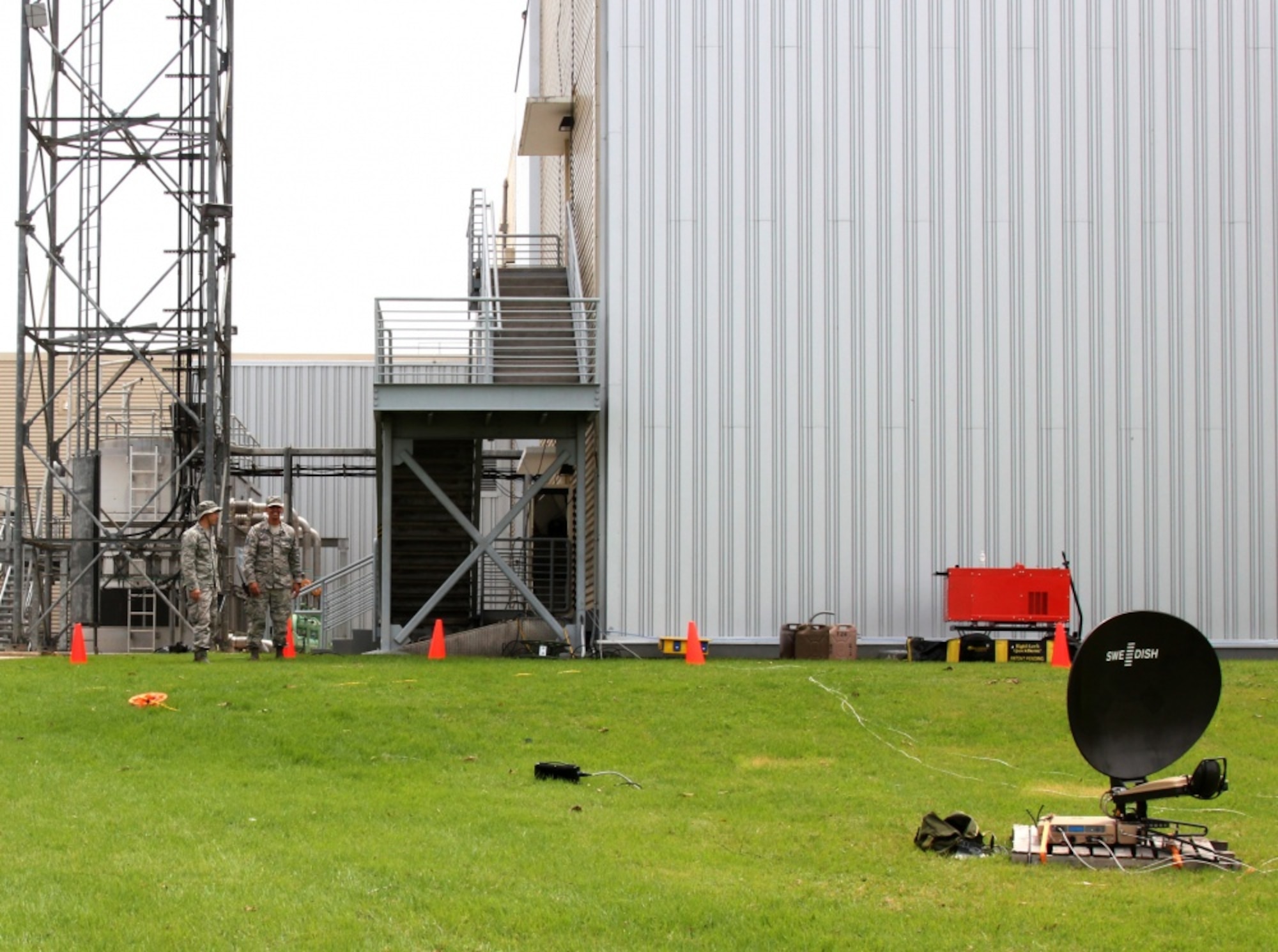 Airmen look at a satellite dish.