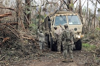 Soldiers clear debris along a roadway.