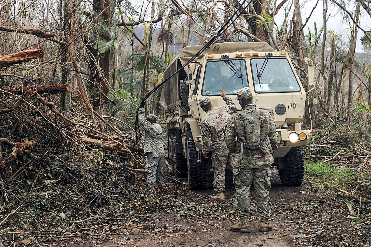 Soldiers clear debris along a roadway.
