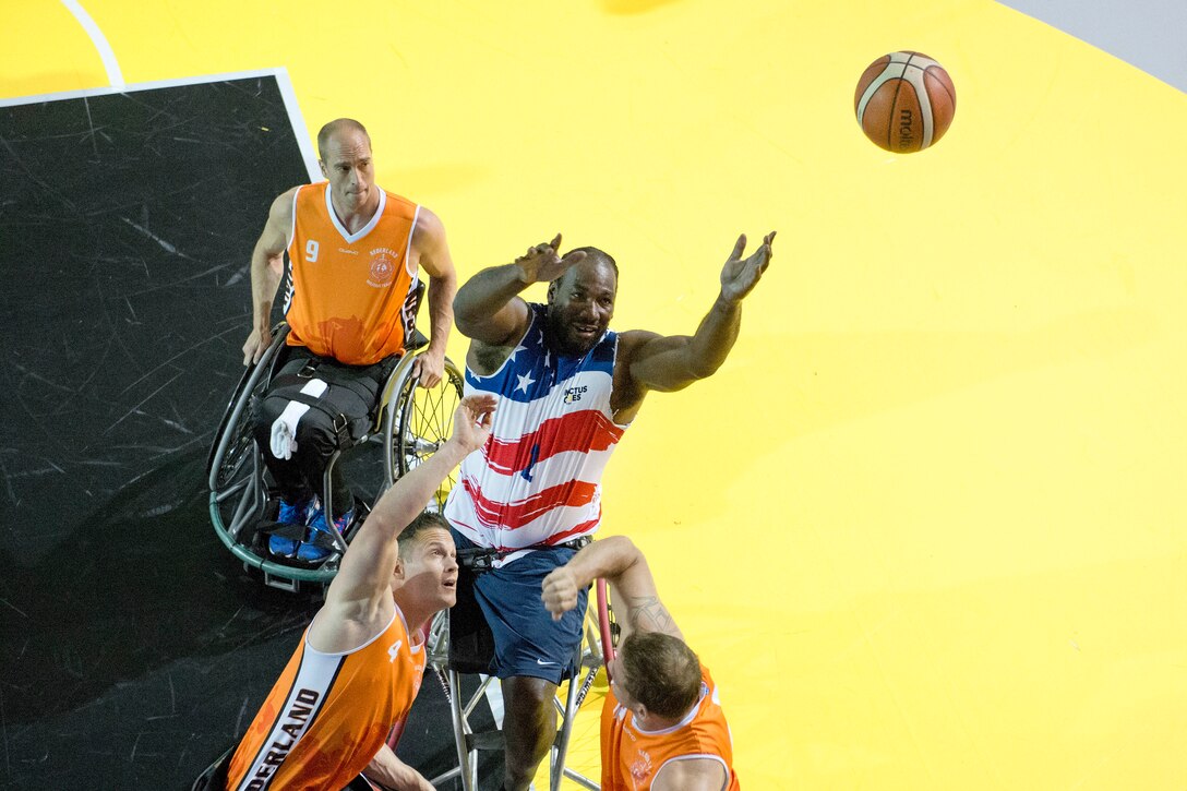 Army Spc. Anthony Pone reaches for a rebound against Netherlands defenders in a preliminary rounds wheelchair basketball game.