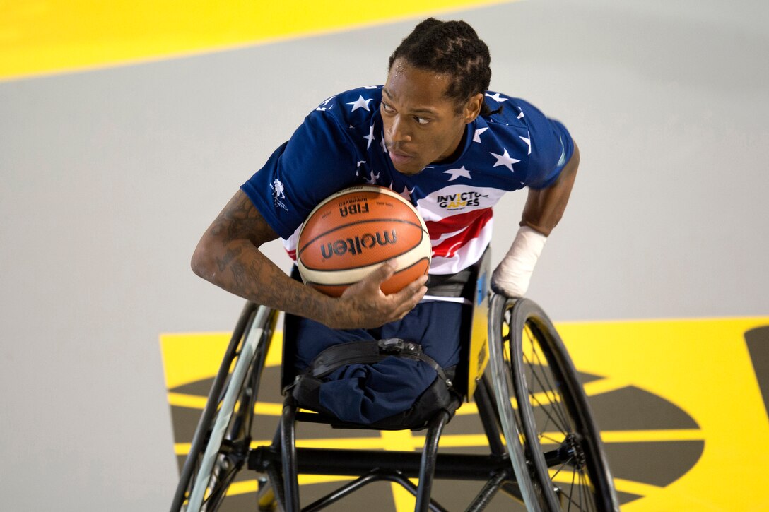 Marine Corp Sgt. Anthony McDaniel protects the ball against Netherlands defenders in a preliminary rounds wheelchair basketball game.