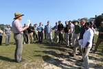 A group of people stand in a circle listening to a tour guide.