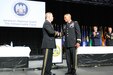 Lt. Gen. Michael Garrett shakes hands with one of the fellow speakers on stage.