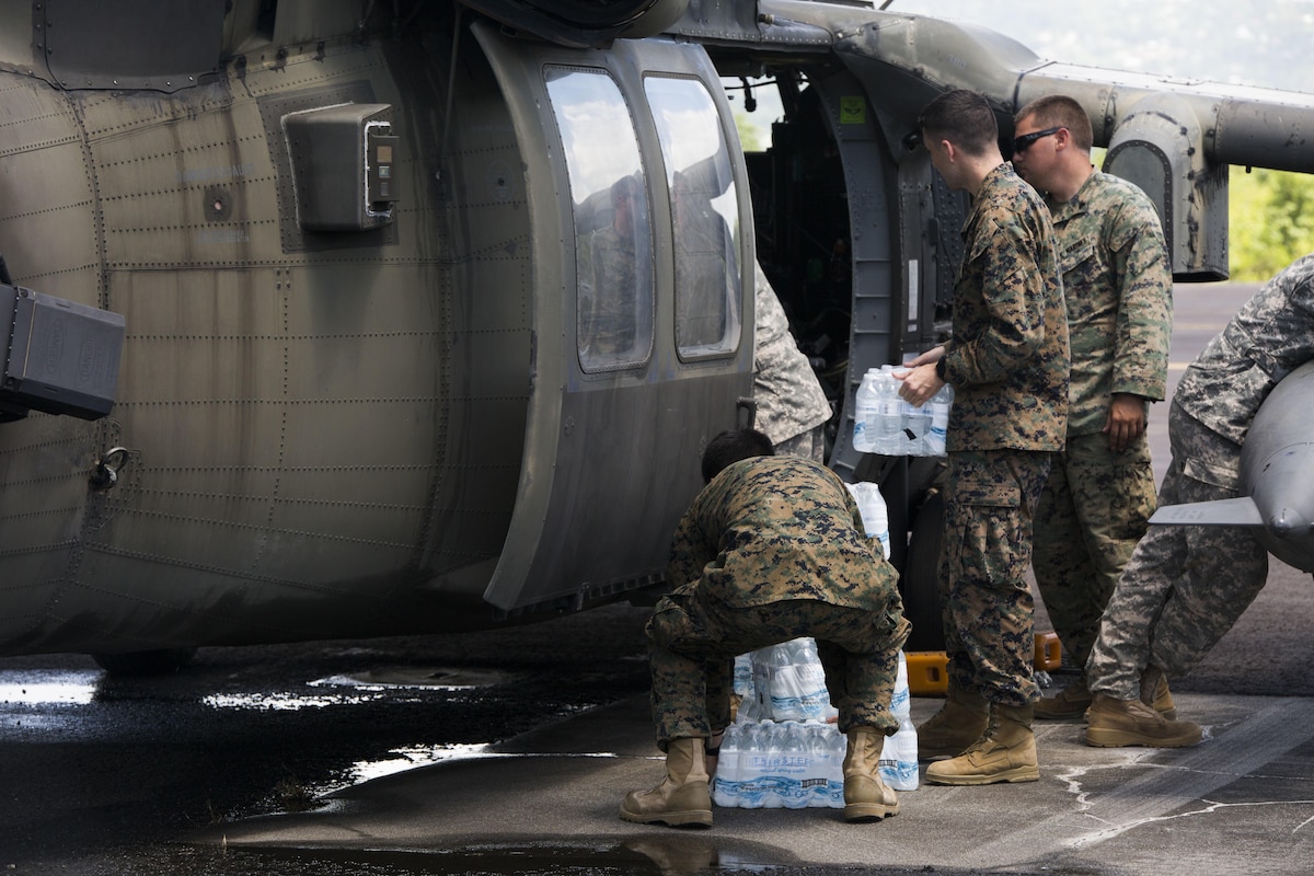 U.S. service members load water into a U.S. Army UH-60 Black Hawk helicopter