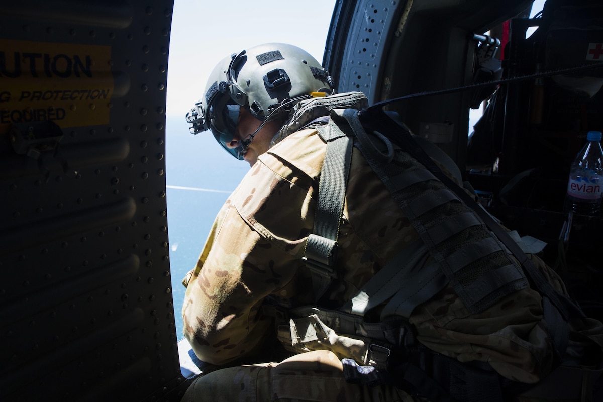 A Soldier looks out of the window of a UH-60 Black Hawk helicopter