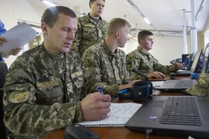 Soldiers look at computer screens.