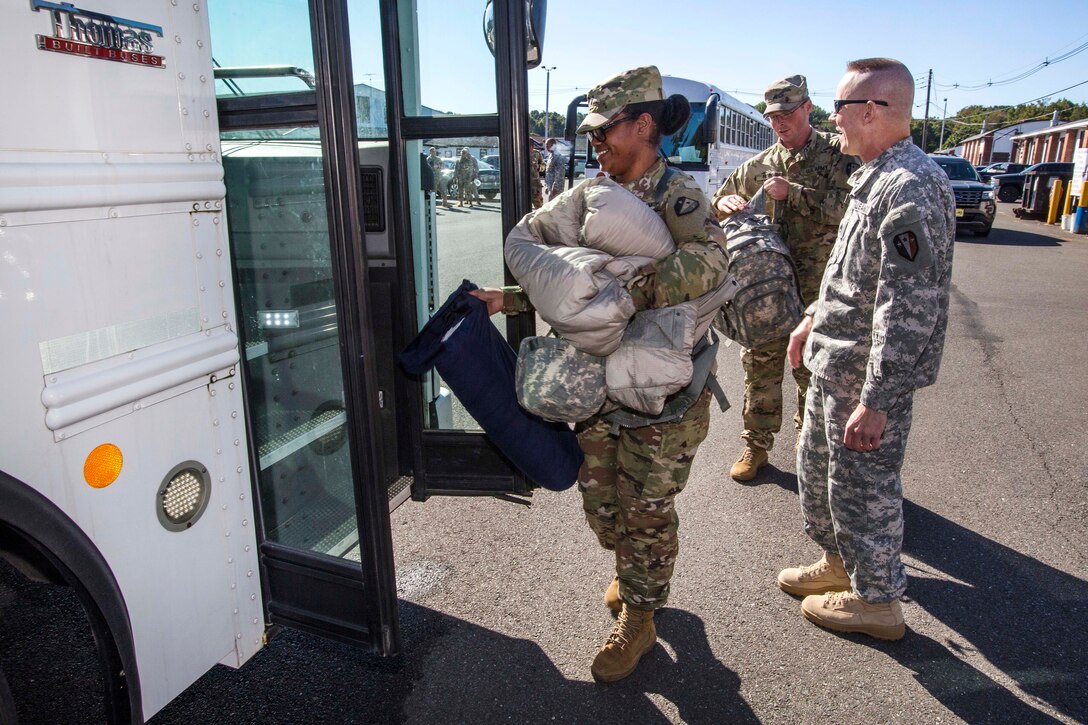 Army National Guardsmen board a bus and prepare to leave the National Guard Armory.