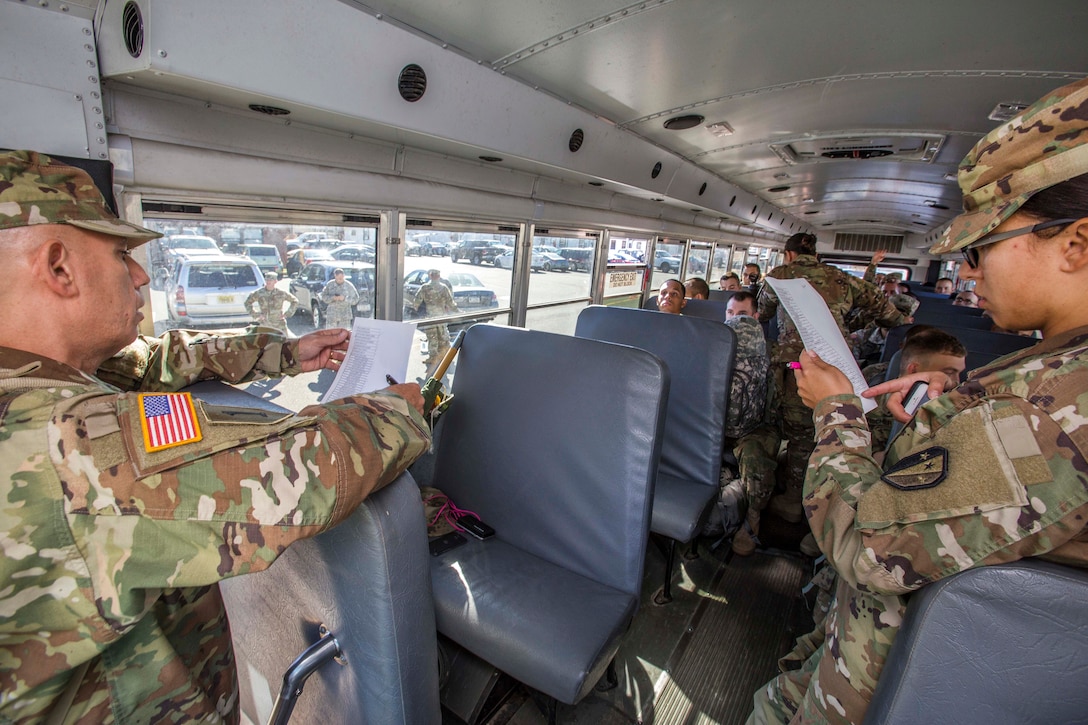 Army National Guard Master Sgt. Ernesto Santiago conducts a roll call of the soldiers on the bus.