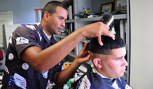 An airman cuts a man's hair.