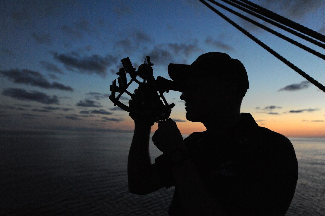 A U.S. Coast Guard Academy officer candidate practices navigating using the stars and a sextant during an evening training session aboard United States Coast Guard Barque Eagle