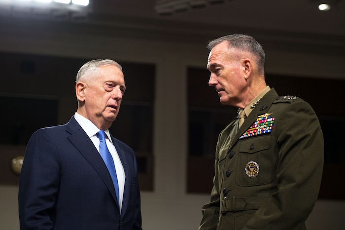 Defense Secretary Jim Mattis speaks with Marine Corps Gen. Joe Dunford while standing in a room.