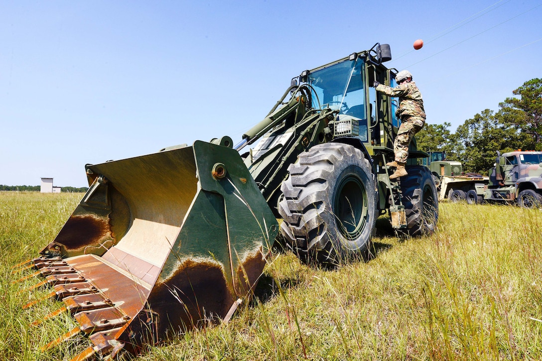 A Guardsman prepares to move a bulldozer and stage it with other heavy equipment .