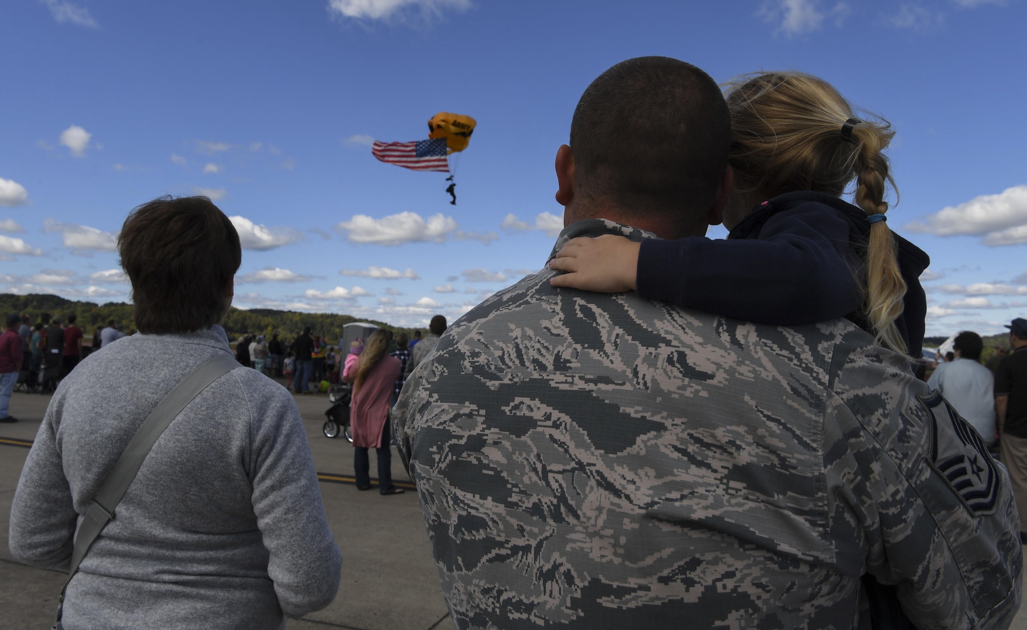 U.S. Air Force Master Sgt. Andy Hill holds his daughter, Elise, while watching as the U.S. Army Golden Knights Parachute Team parachute from the sky Sept. 30, 2017 during the 70th Anniversary Air Show at McLaughlin Air National Guard Base, Charleston, W.Va. 2017 marks the 70th Anniversary of the founding of McLaughlin Air National Guard Base and Yeager Airport which were named in honor of Brig. Gen. James McLaughlin and Brig. Gen. Chuck Yeager, respectfully. (U.S. Air National Guard photo by Airman Caleb Vance)