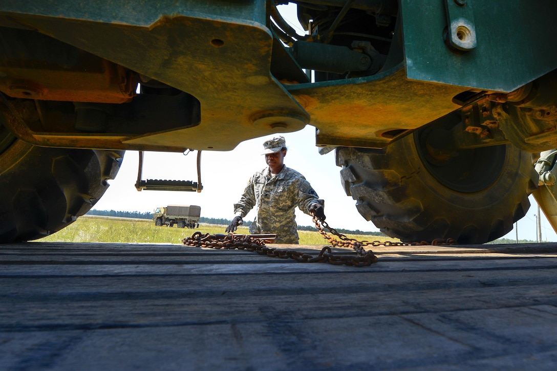 Army Spc. Lachanda Jackson unloads heavy equipment off from a flatbed truck.