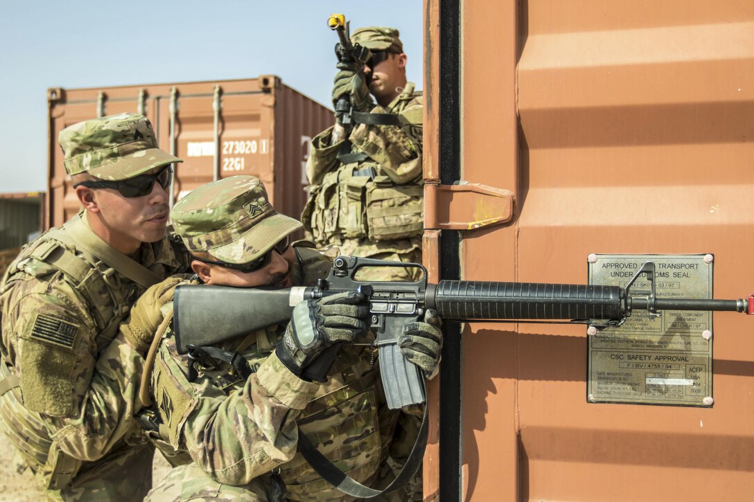 Two soldiers aim weapons while a third soldier offers guidance.