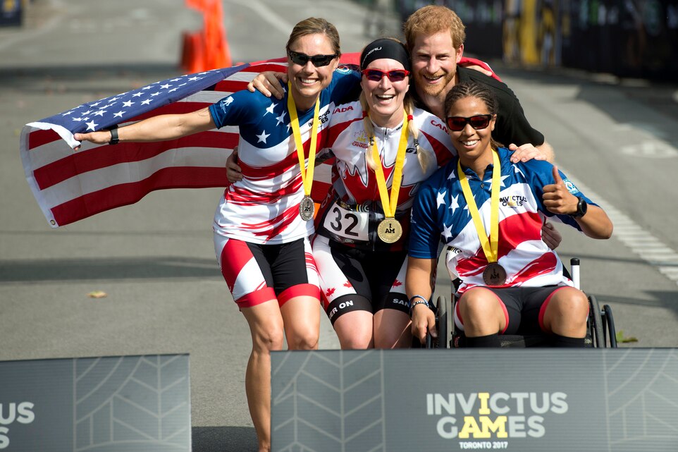 Air Force Tech. Sgt. Lara Mastel, left, and Marine Corps veteran Sgt. Gabby Graves-Wakes, right, pose at the medal podium with a Canadian competitor and Britain's Prince Harry.