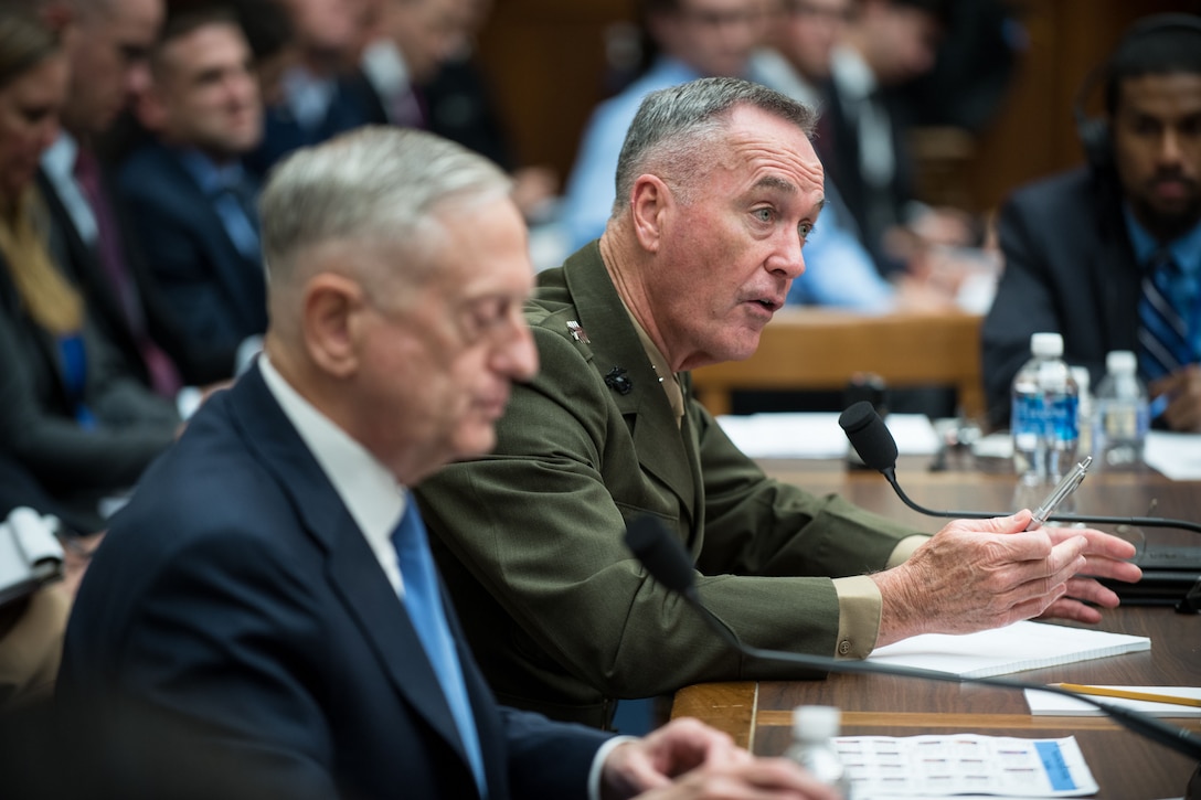 Defense Secretary Jim Mattis and the chairman of the Joint Chiefs of Staff sit at a desk and talk.